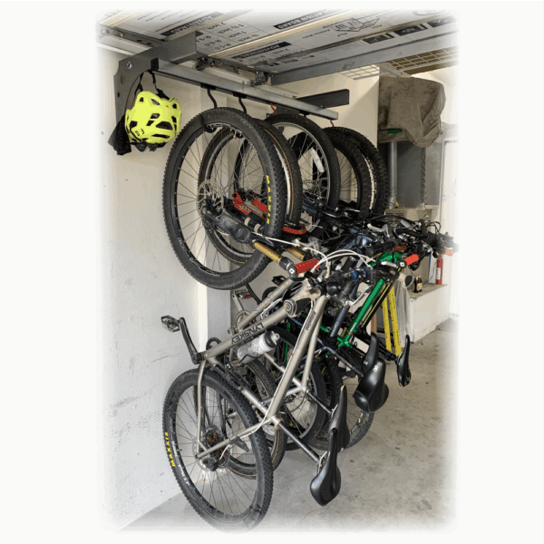 Wall mounted sliding bike storage rack under garage door rail holding five bikes and a helmet. Wall mounted sliding bike storage rack under garage door rail holding five bikes and a helmet.